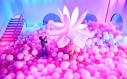 Person exploring pink balloon installation at Bubble Planet, Seattle.