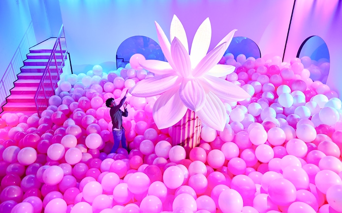 Person exploring pink balloon installation at Bubble Planet, Seattle.