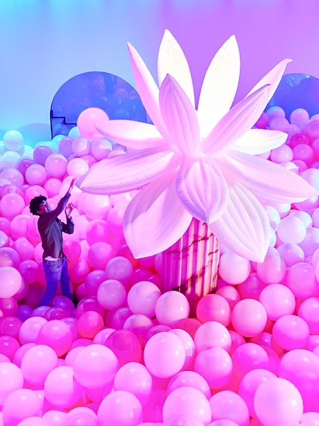 Person exploring pink balloon installation at Bubble Planet, Seattle.