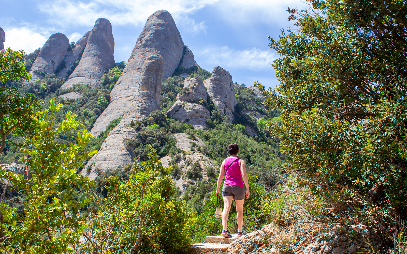 Hiker on Montserrat mountain trail with rocky peaks in the background, near Barcelona.