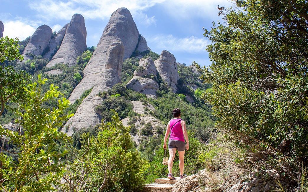 Hiker on Montserrat mountain trail with rocky peaks in the background, near Barcelona.