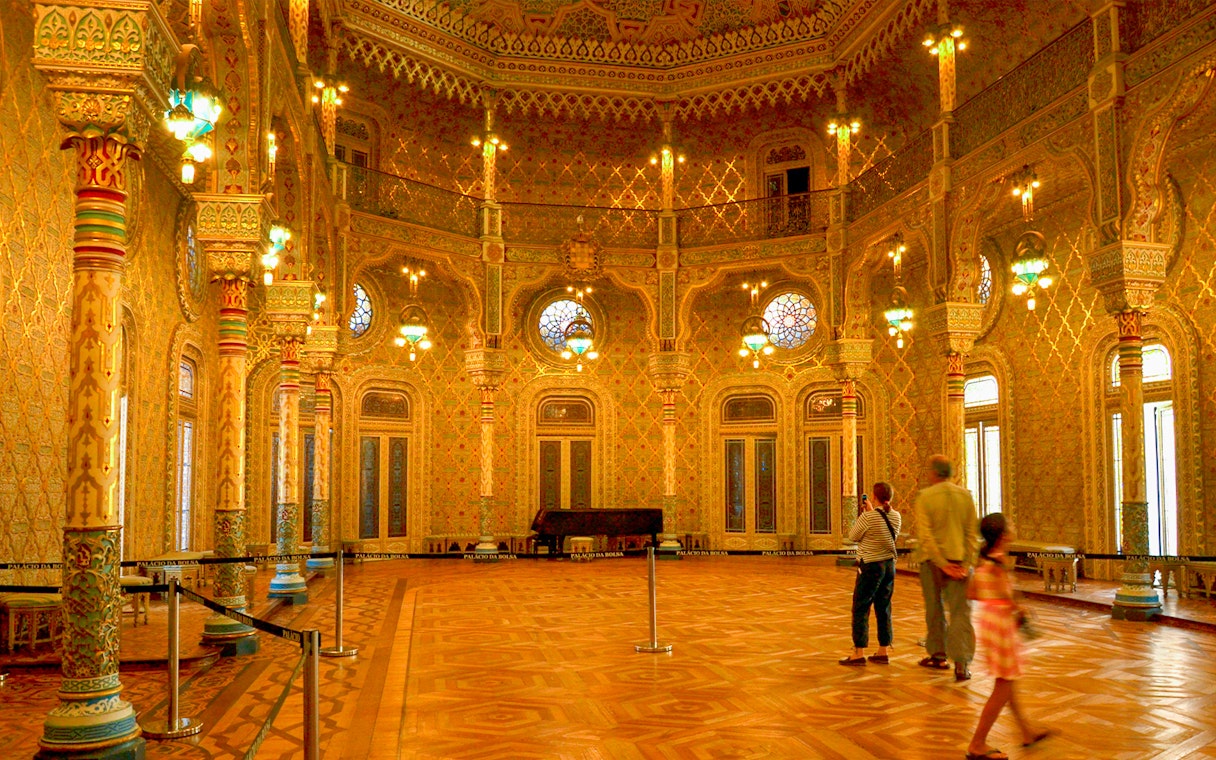 Moorish Salon in Palácio da Bolsa, Porto, with intricate columns and stained glass windows.