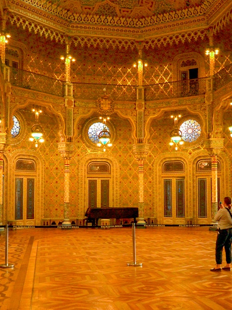 Moorish Salon in Palácio da Bolsa, Porto, with intricate columns and stained glass windows.