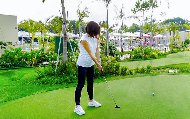 Person playing mini-golf on a lush green course at UltraGolf.