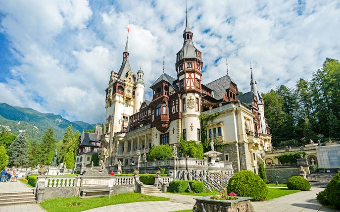 Peles Castle exterior with ornate architecture and surrounding gardens in Sinaia, Romania.