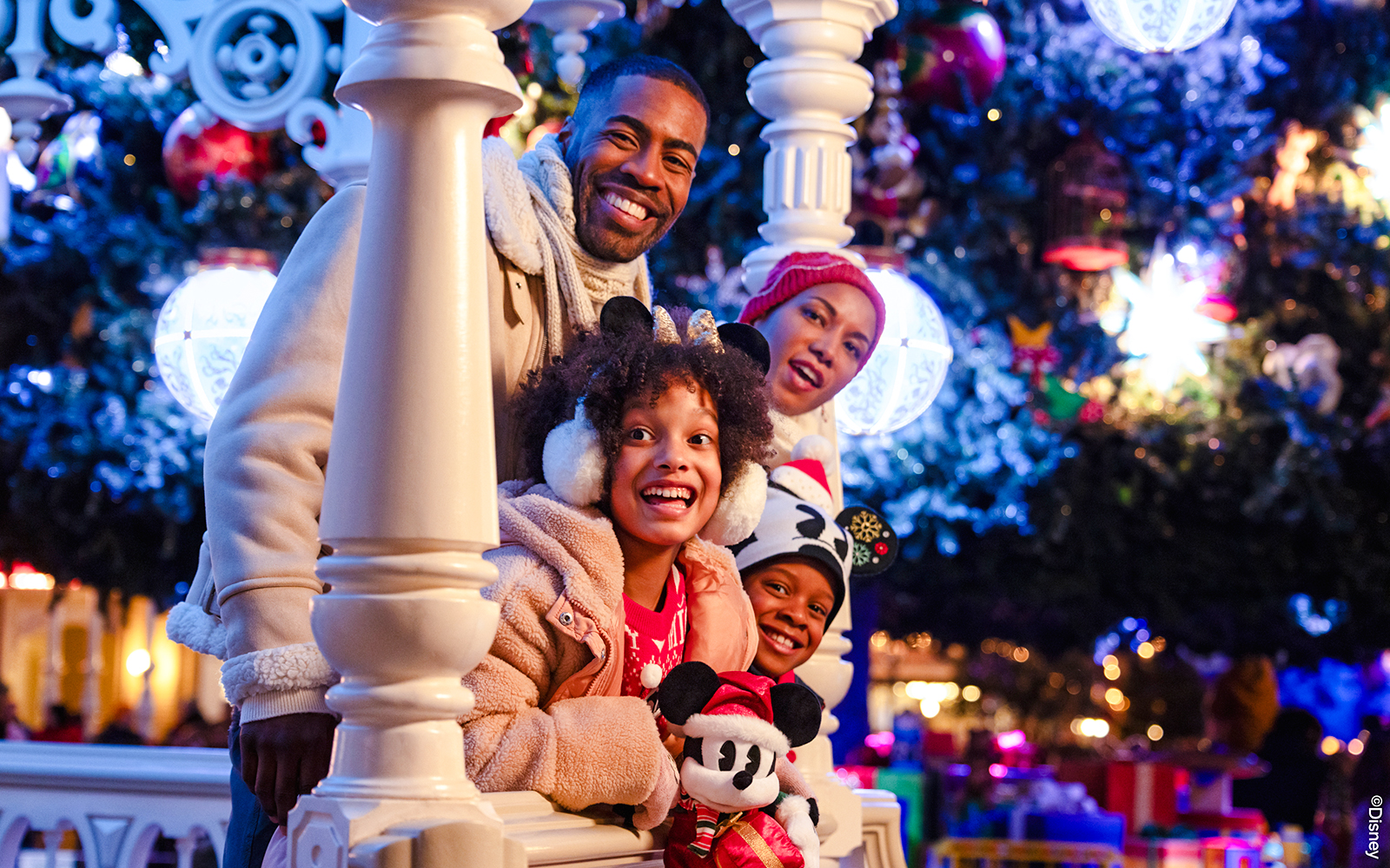 Family enjoying Disneyland Christmas 2025 with festive decorations and Mickey Mouse plush.