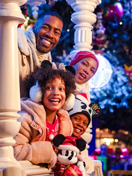 Family enjoying Disneyland Christmas 2025 with festive decorations and Mickey Mouse plush.
