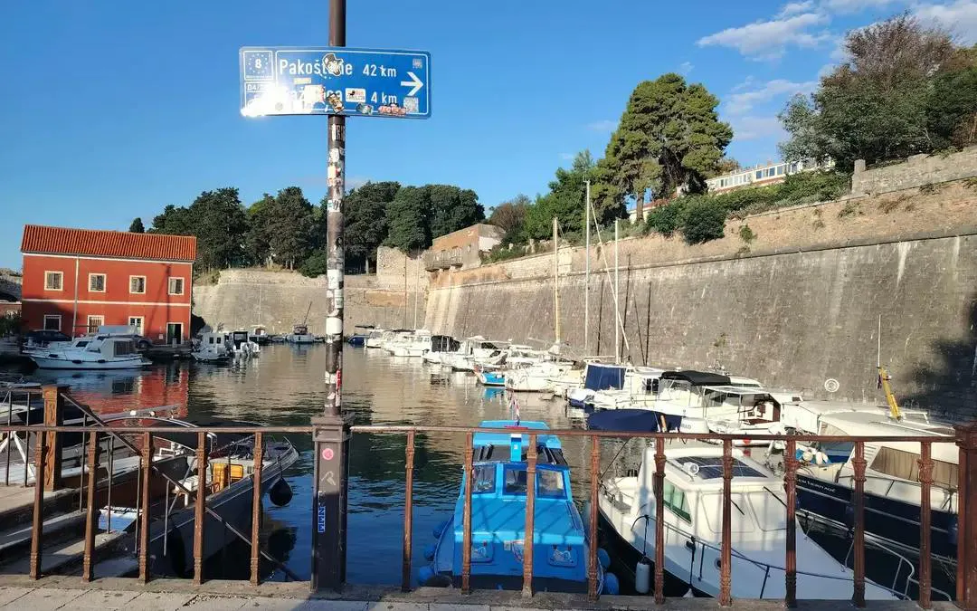 Boats docked in a historic harbor with stone walls in Zadar, Croatia.