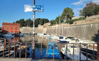 Boats docked in a historic harbor with stone walls in Zadar, Croatia.