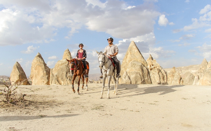 Horseback riders in Cappadocia's unique rock formations during a 2-hour tour.