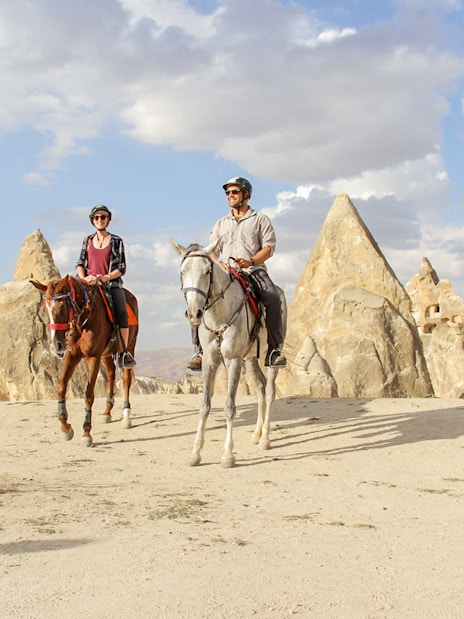 Horseback riders in Cappadocia's unique rock formations during a 2-hour tour.