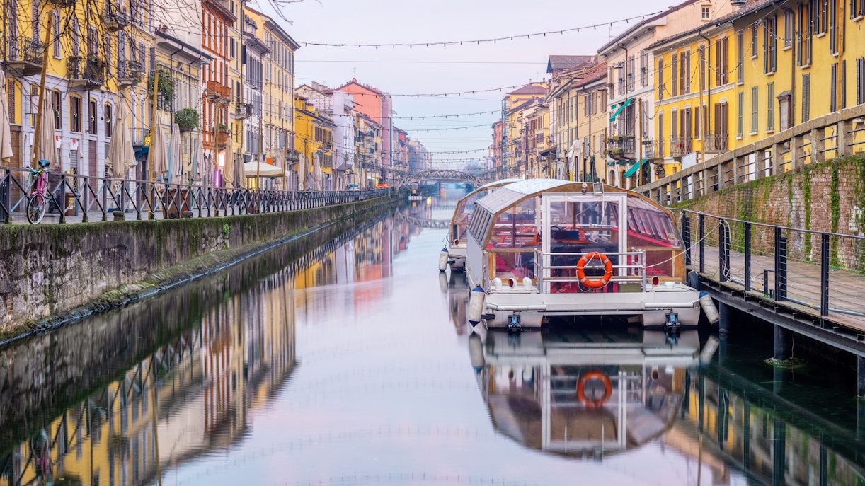 Boat on Navigli canal with colorful buildings in Milan.