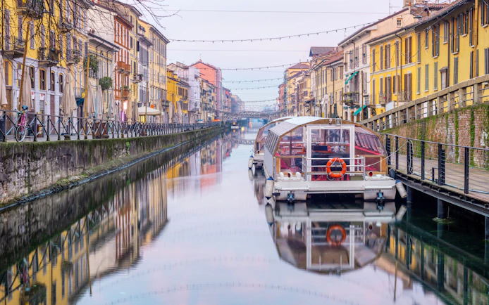 Boat on Navigli canal with colorful buildings in Milan.