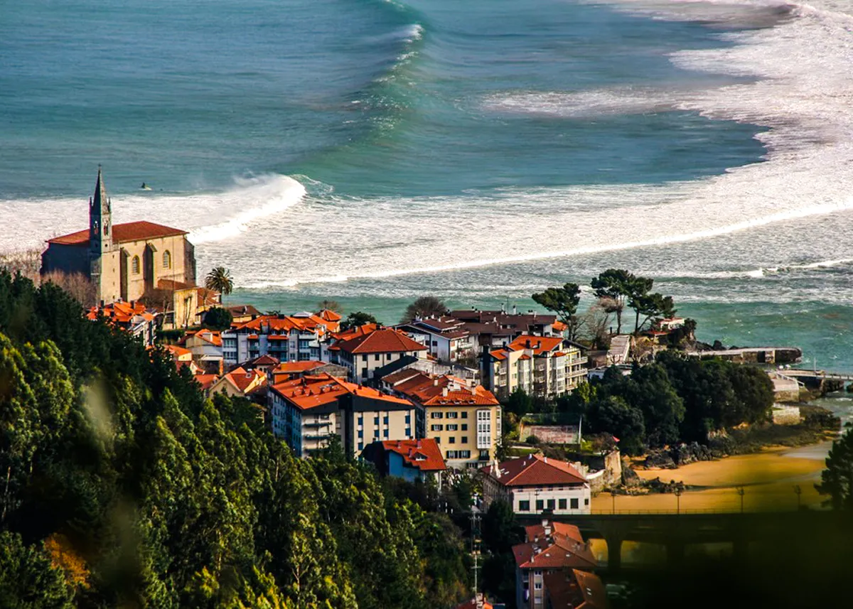 Coastal view of Mundaka village with church and ocean waves, near Bilbao, Spain.