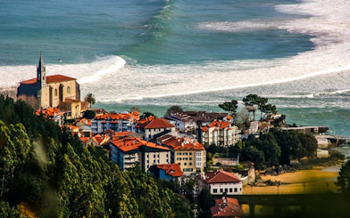 Coastal view of Mundaka village with church and ocean waves, near Bilbao, Spain.