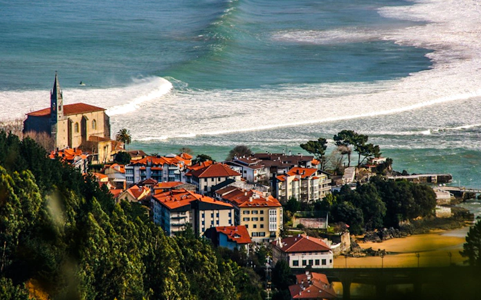 Coastal view of Mundaka village with church and ocean waves, near Bilbao, Spain.