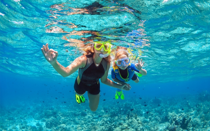 Tourists snorkelling over coral reefs at Sesimbra Beach, Portugal.