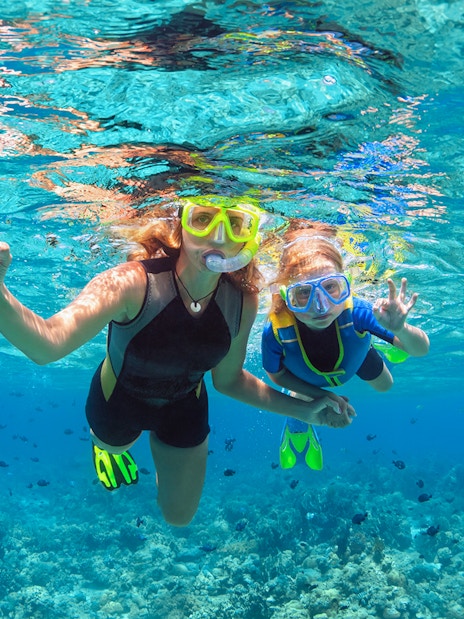 Tourists snorkelling over coral reefs at Sesimbra Beach, Portugal.