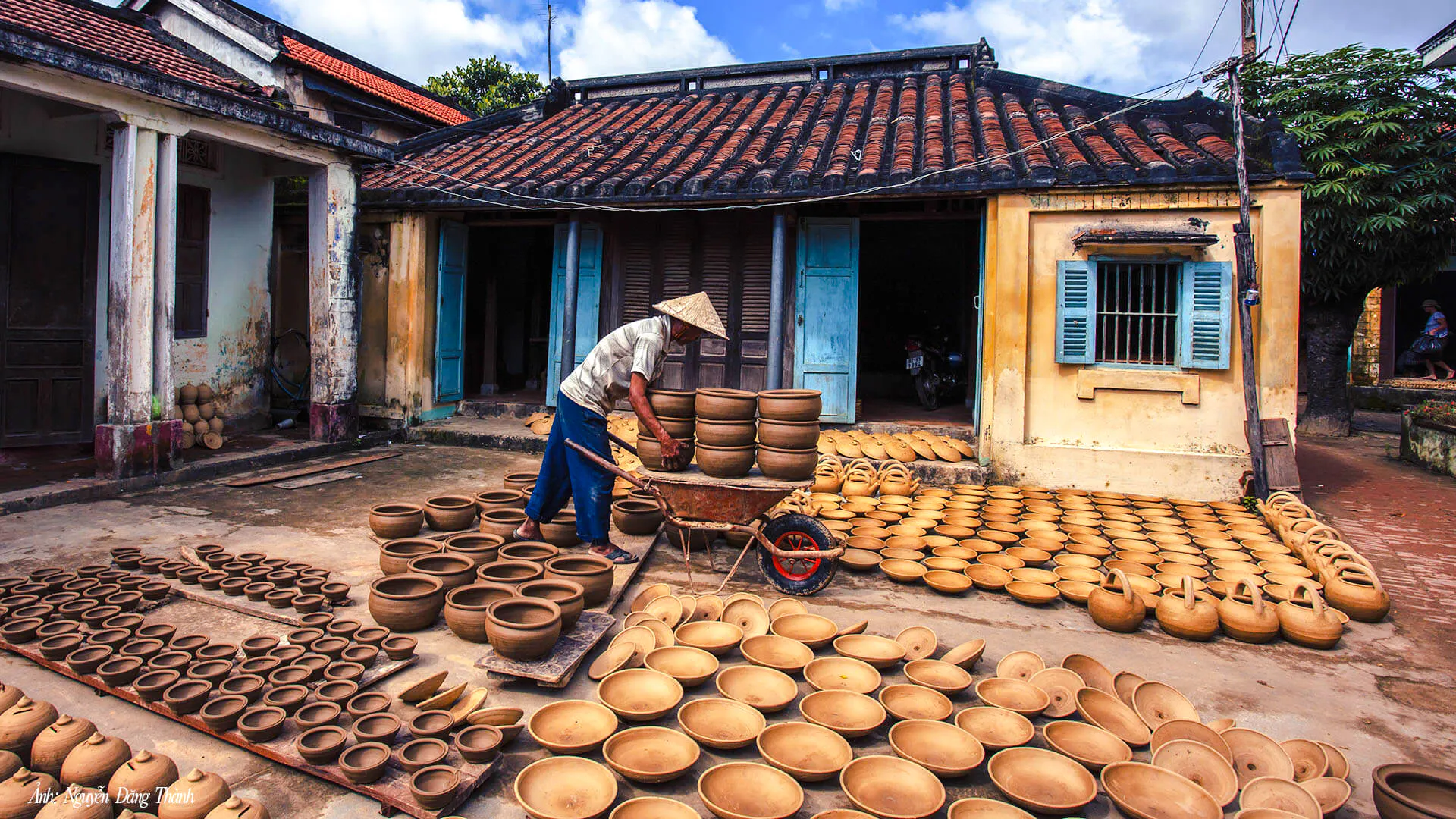 Craftsman arranging pottery in a traditional courtyard during the 3 Heritage Craft Hoi An Villages Tour by Bicycle.