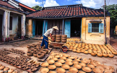 Craftsman arranging pottery in a traditional courtyard during the 3 Heritage Craft Hoi An Villages Tour by Bicycle.