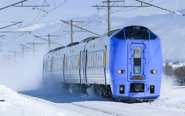 Blue train traveling through snowy landscape in Sapporo-Noboribetsu area.
