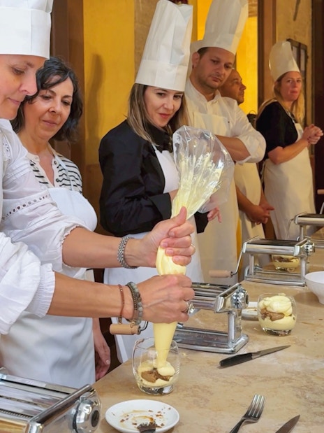Participants making Tiramisu in a cooking class in Siena.