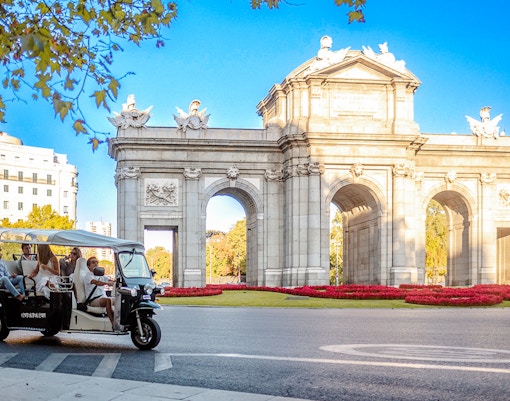 Eco Tuk Tuk tour passing by Puerta de Alcalá in Madrid.