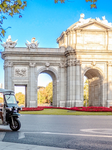 Eco Tuk Tuk tour passing by Puerta de Alcalá in Madrid.