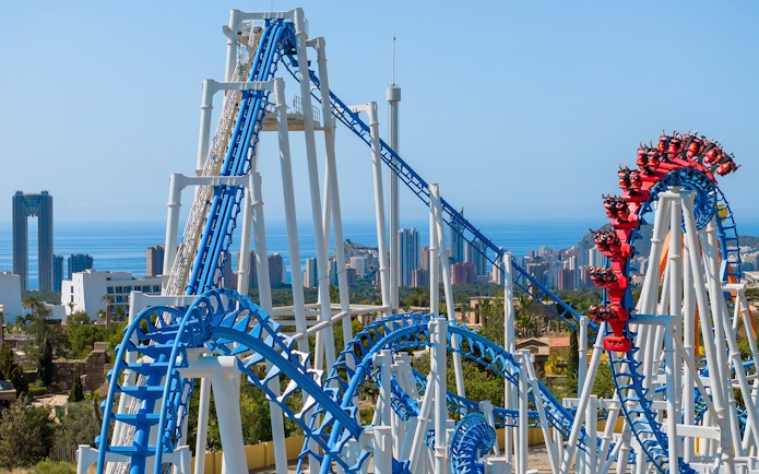 Roller coaster at Terra Mitica Benidorm with city skyline and sea in the background.