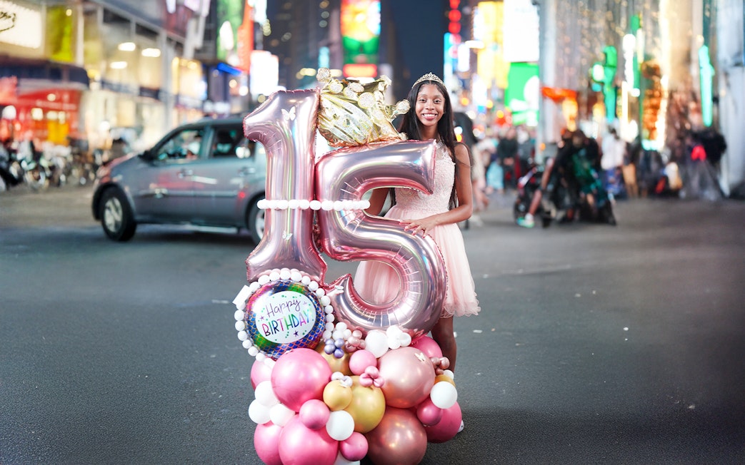 Birthday girl with balloons celebrating sweet 16 in Times Square, NYC.