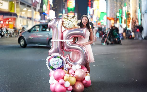 Birthday girl with balloons celebrating sweet 16 in Times Square, NYC.