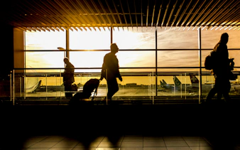 Travelers with luggage walking through airport terminal at sunset, Zanzibar transfers.
