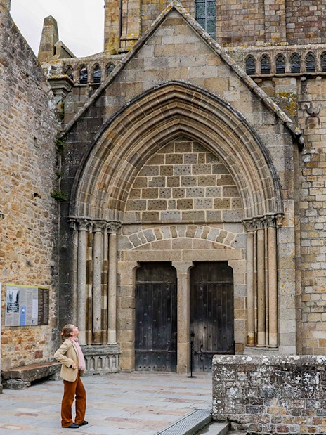Tourist exploring Mont St. Michel Abbey's historic entrance on a full-day tour from Paris.