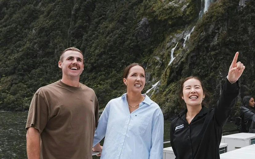 Couple with guide at Milford Sound, enjoying scenic views on VIP cruise from Queenstown.