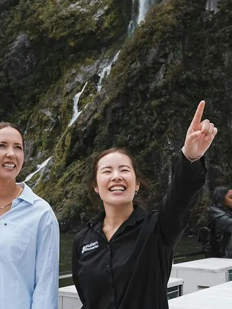 Couple with guide at Milford Sound, enjoying scenic views on VIP cruise from Queenstown.