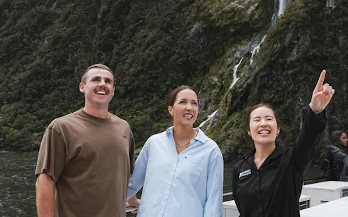 Couple with guide at Milford Sound, enjoying scenic views on VIP cruise from Queenstown.
