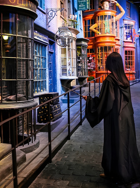Person in robe with wand on Diagon Alley at Harry Potter London tour.
