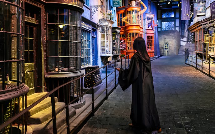 Person in robe with wand on Diagon Alley at Harry Potter London tour.