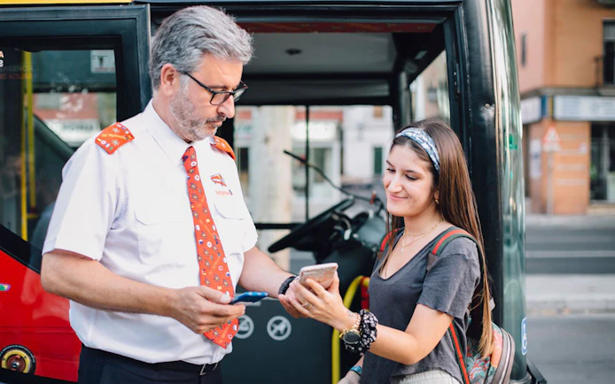 Bus driver assisting tourist with ticket on Thessaloniki Hop-On-Hop-Off Tour.