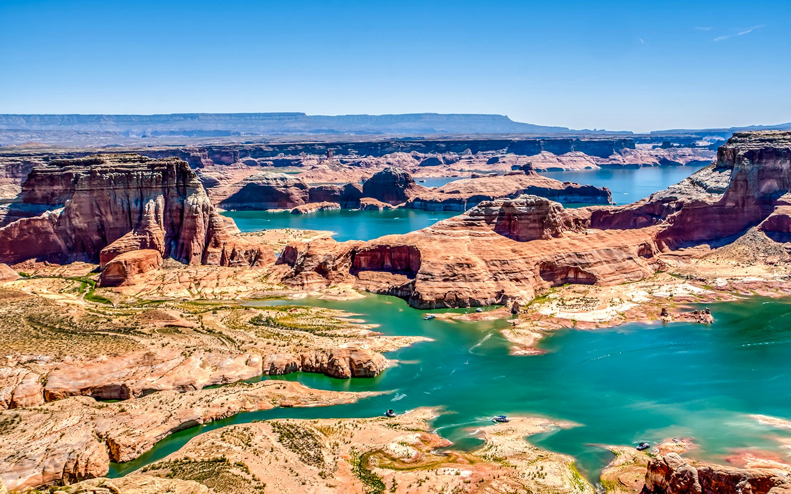 Lake Powell with red rock formations and turquoise water, showcasing slot canyons.