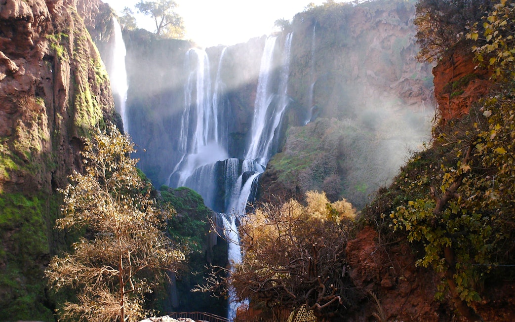 Ouzoud Waterfalls cascading over cliffs surrounded by lush greenery in Morocco.