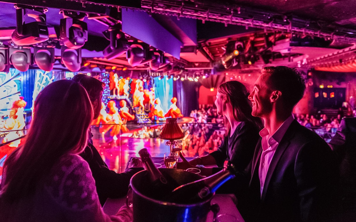 Tourists enjoying champagne at a Moulin Rouge show in Paris.