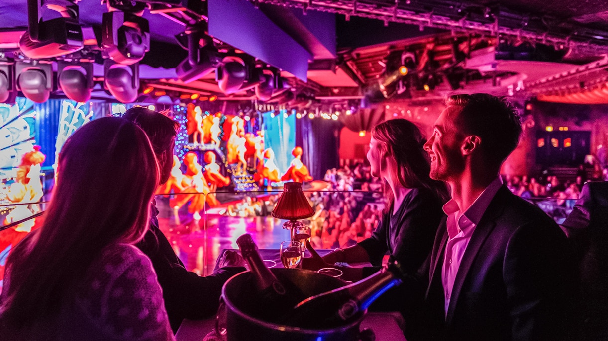 Turistas disfrutando del champán en el Moulin Rouge, París.