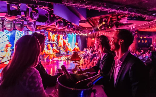 Tourists enjoying champagne at a Moulin Rouge show in Paris.