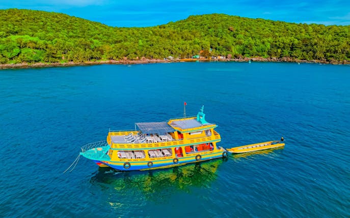 Boat on Phu Quoc 3-island tour with lush green hills in background.