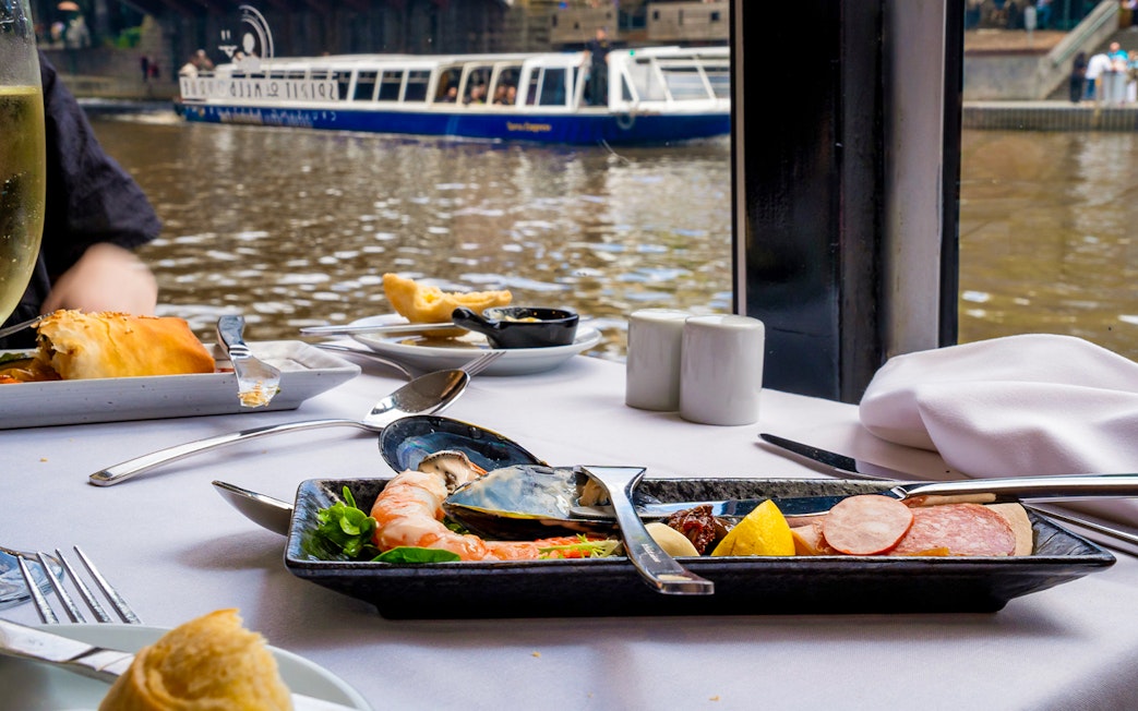 Dining table with seafood platter on Spirit of Melbourne cruise, river view in background.