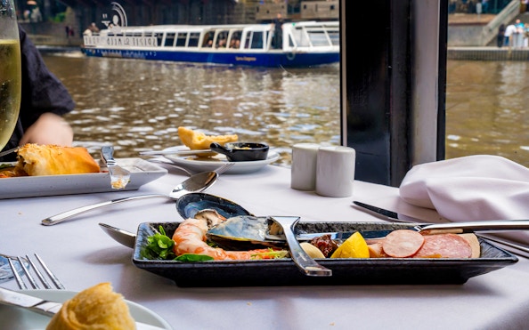 Dining table with seafood platter on Spirit of Melbourne cruise, river view in background.