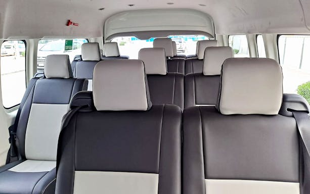 Shuttle bus interior with black and white seats for Global Village tour.