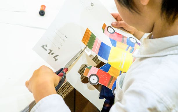 Child cutting colorful paper at teamLab Future Park workshop.