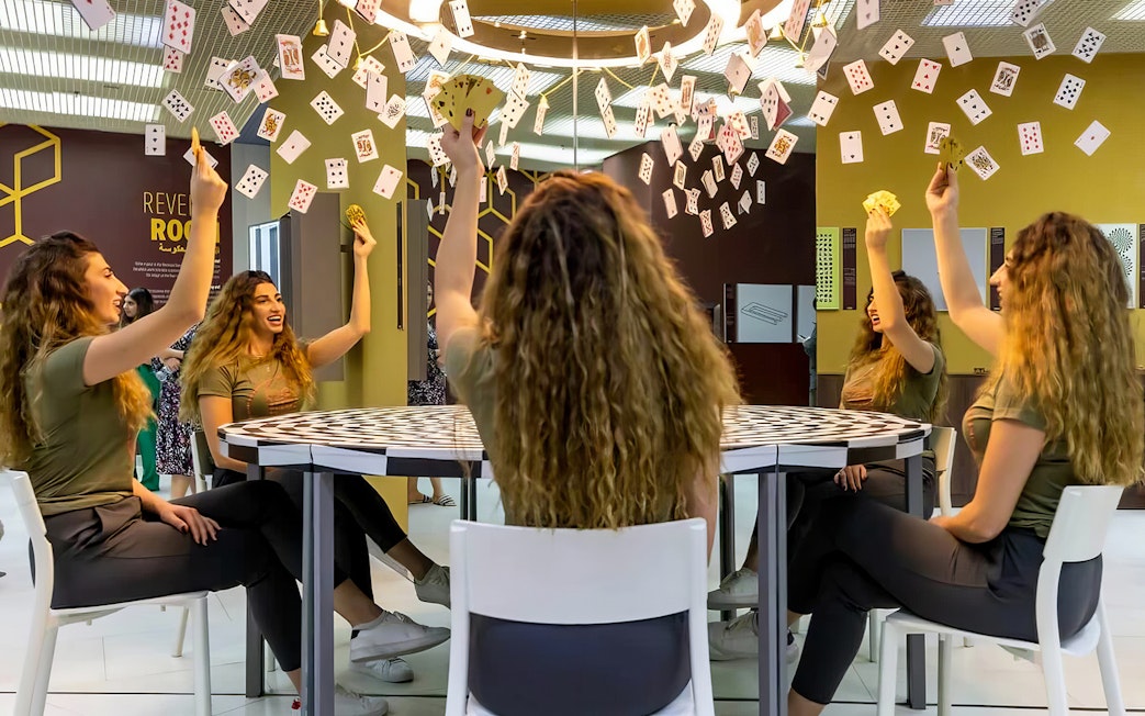 Visitors experiencing optical illusions with mirrors and cards at Museum of Illusions Dubai.